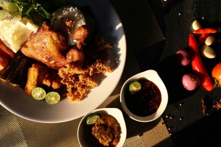 A balanced flexitarian meal featuring grilled chicken, steamed rice, fresh vegetables, and dipping sauces, captured in warm sunlight.