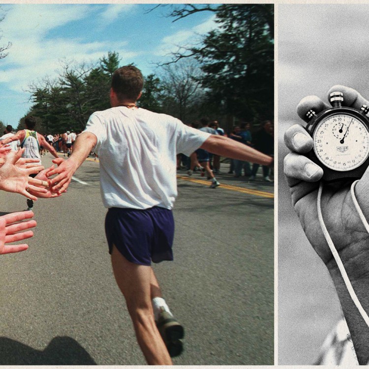 Runner high-fiving spectators at the Boston Marathon alongside a coach holding a stopwatch
