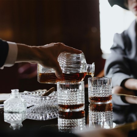 A person pouring whiskey into two different glasses for a woman